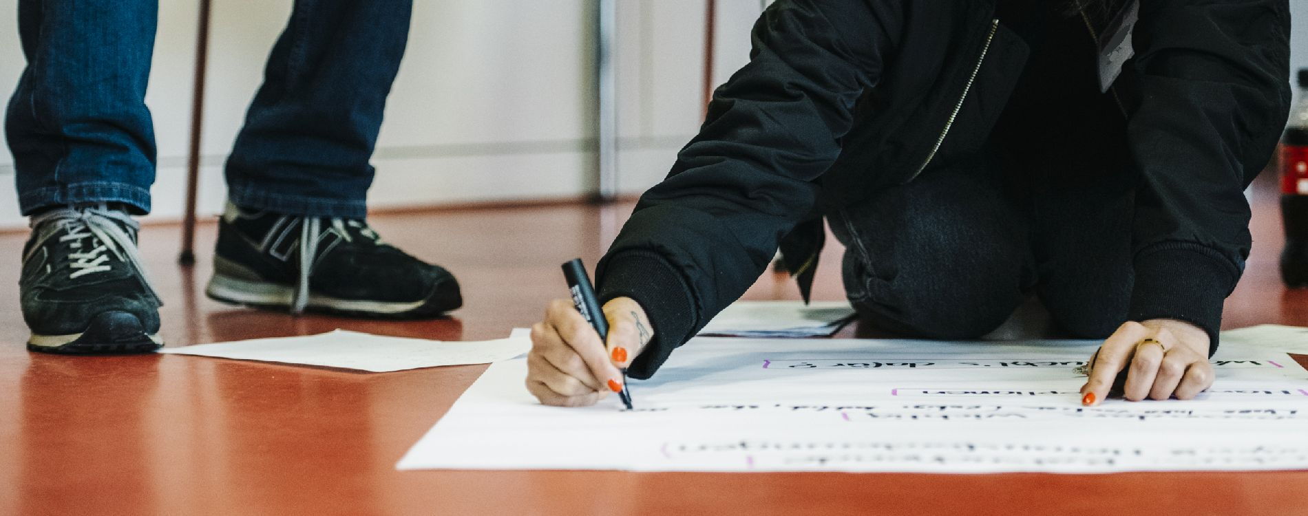 Teilnehmende eines Workshops schreiben auf ein Flipchart-Papier