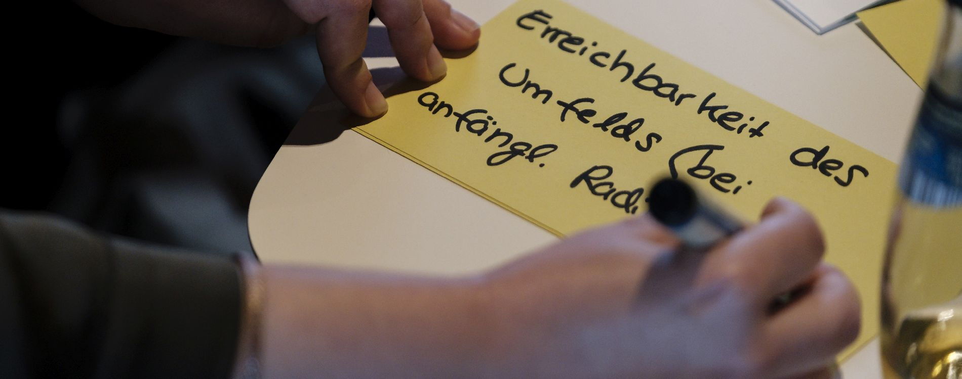 Person schreibt "Erreichbarkeit des Umfelds bei amfänglicher Radikalisierung" auf eine Moderationskarte